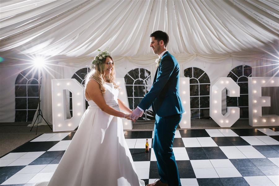 Wedding couple dance on checker board floor in front of light up 'dance' feature