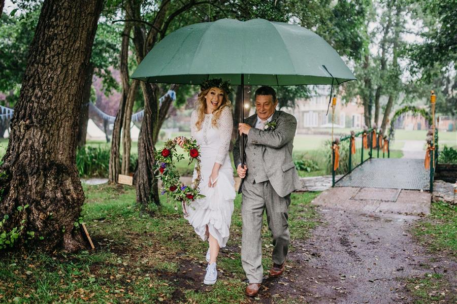 Happy bride with father of the bride under umbrella