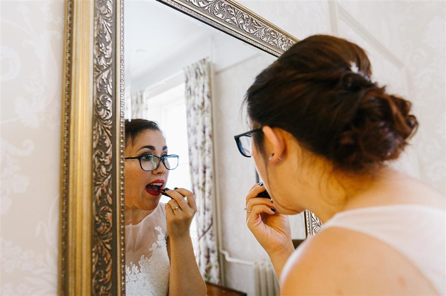 Bride applies Illamasqua lipstick in a mirror