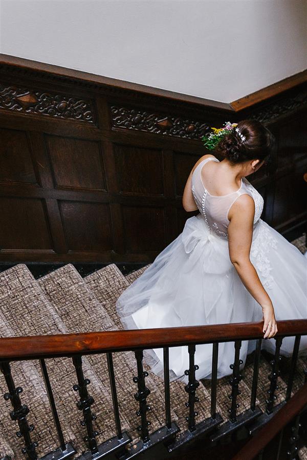 Bride wearing white button up wedding dress going down the stairs