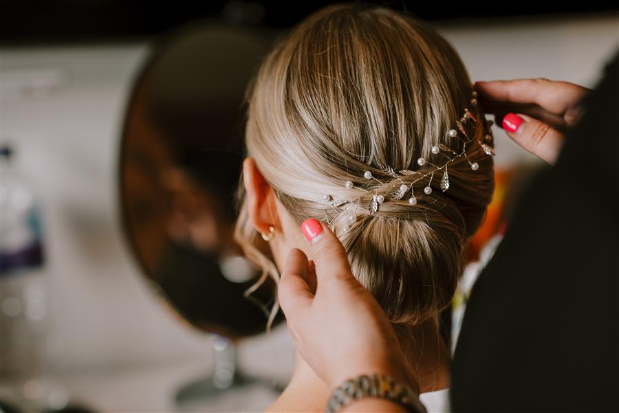 Mon Amie Wedding Hairstylist adjusting hair vine on a blonde wedding client