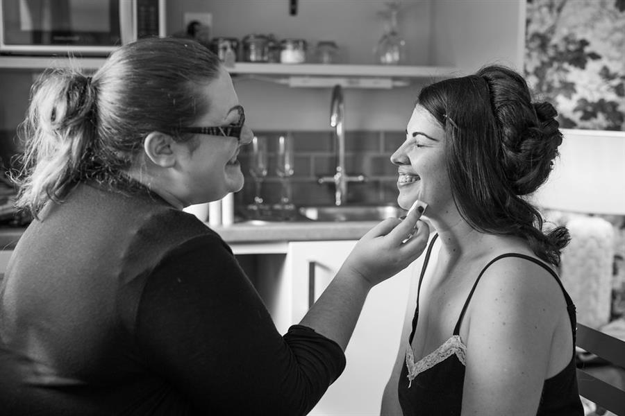 Smiling Ms Moo applies makeup to a smiling bride to be