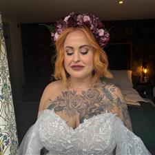 Copper haired bride has pink and purple makeup with similarly coloured flower crown