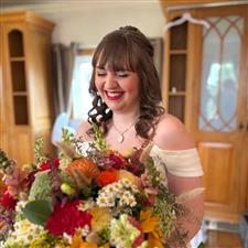 Brunette bride laughs looking at her bright colourful bouquet wearing red lipstick