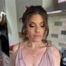 Bride in soft pink dress has yellow, orange, pink and purple eyeshadow with no lipstick