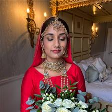 Asian bride wearing red dress with gold jewellery and red lipstick