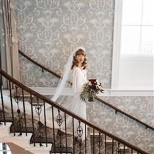 Vintage styled bride looks up at camera from grand staircare