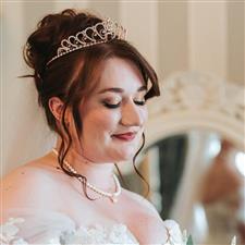 Brunette bride with tiara looks down at bouquet