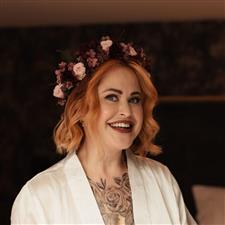 Alternative red haired bride smiles past camera with purple flower crown on