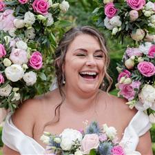 Bride laughs off camera surrounded by her pink bridesmaid bouquets