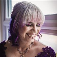 Grinning bride with purple hair, purple wedding dress, and purple eyshadow