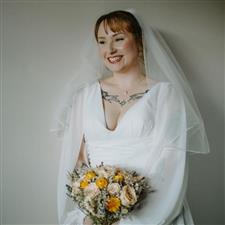 Tattooed bride smiles off camera with white dress and veil