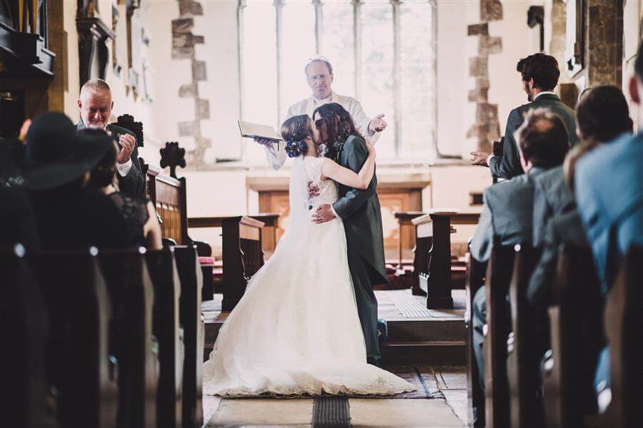 Wedding kiss at the end of the aisle of a church