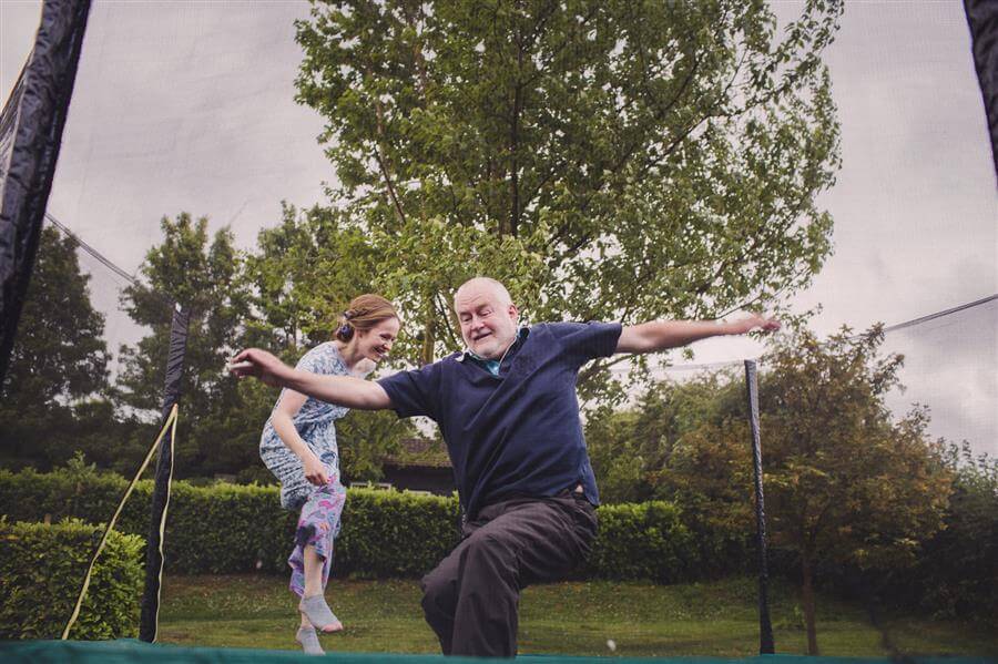 Bride and father bounce on a trampoline