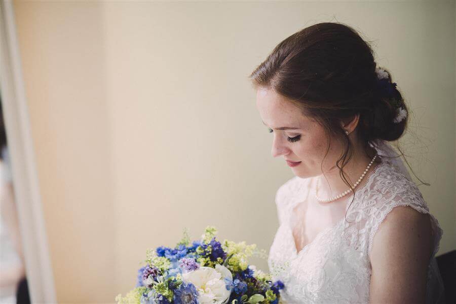 Bride looks at bouquet in portrait with Ms Moo Make Up by Kathryn Edwards Photography