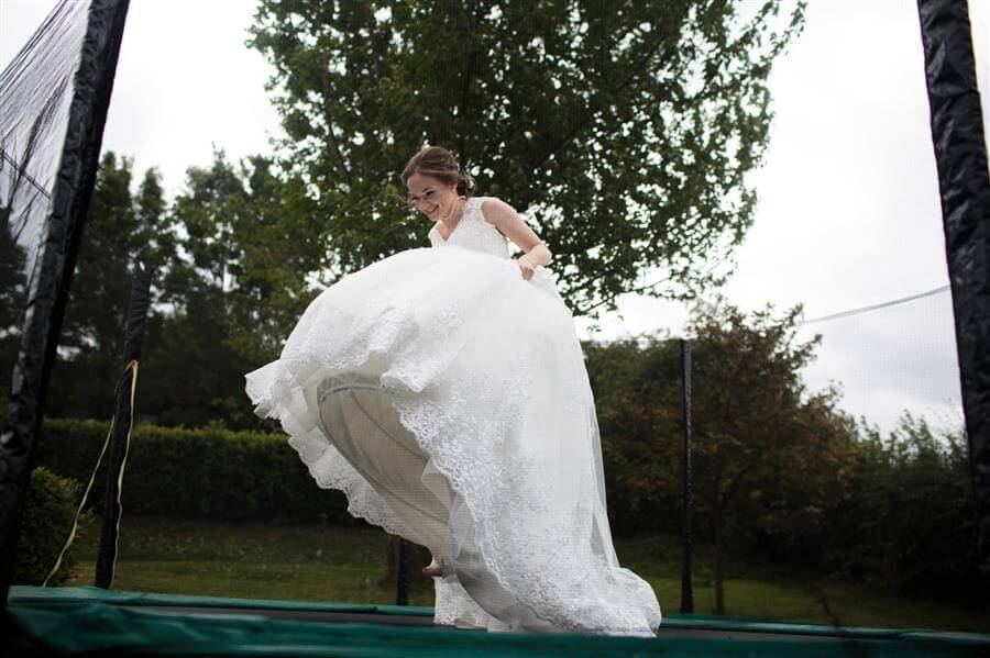 Bride in her wedding dress bounces on a large trampoline