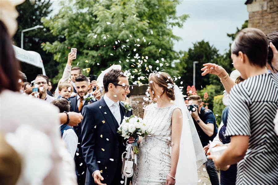 Wedding couple smiling at each other under confetti 