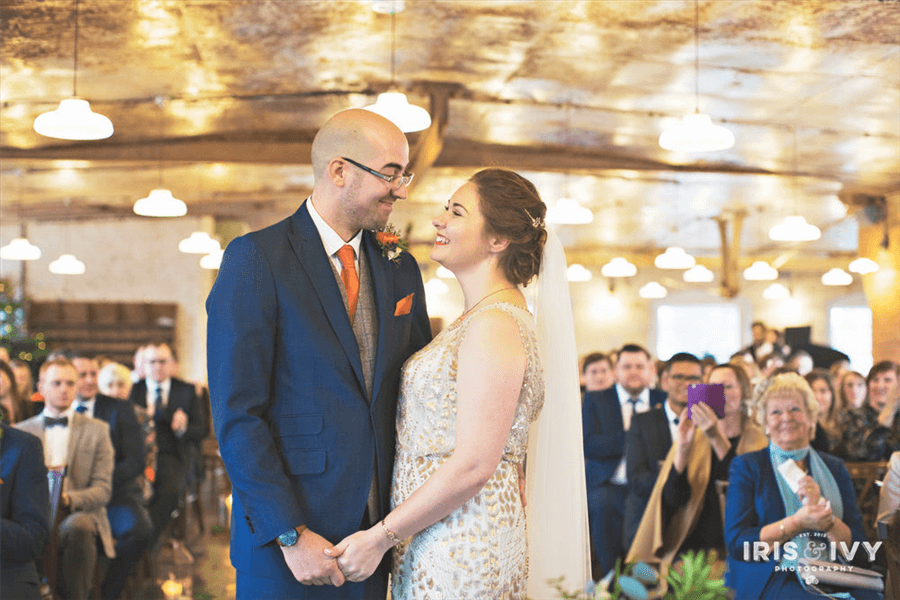 Bride and groom smile at each other in front of their congregation