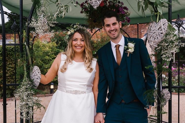 Bride and groom smile at camera under pagoda at The Walled Garden Beeston