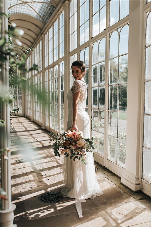 Bride standing in long elegant white wedding dress with large bouquet