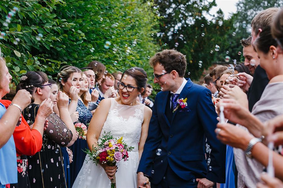 Wedding couple surrounded by bubbles and wedding guests