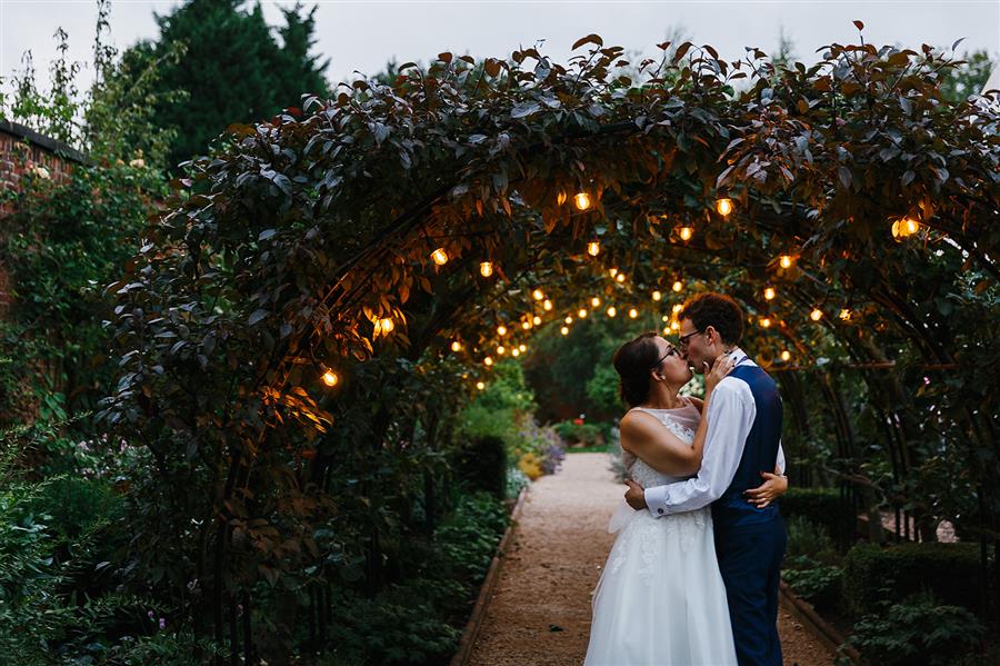 Wedding couple share a kiss under archway in Nottingham