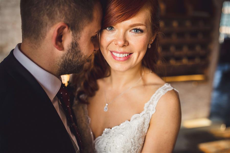 Bride looks at camera embracing husband on wedding day by Matt Brown Photography