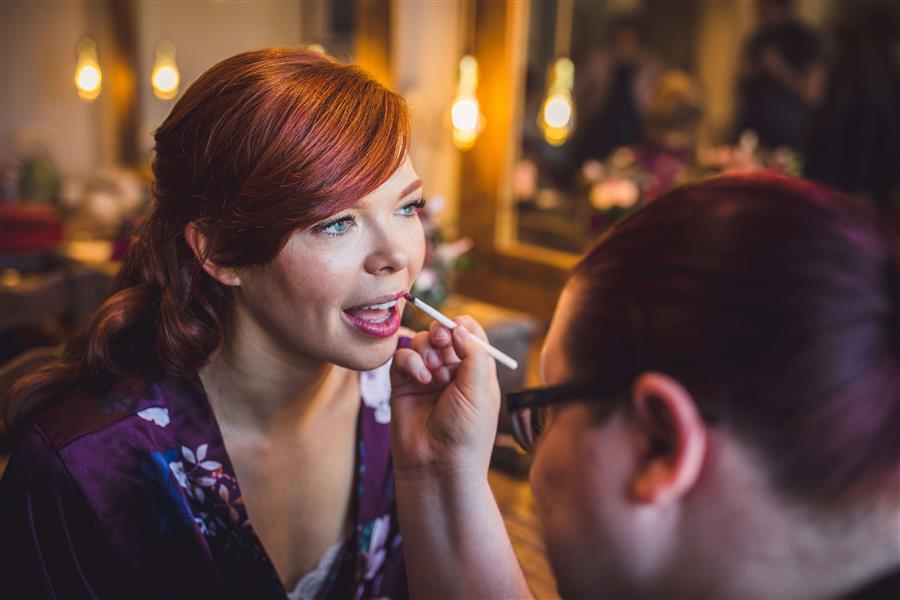 Ms Moo Make Up applying lipstick to a bride to be with sweeping red hair