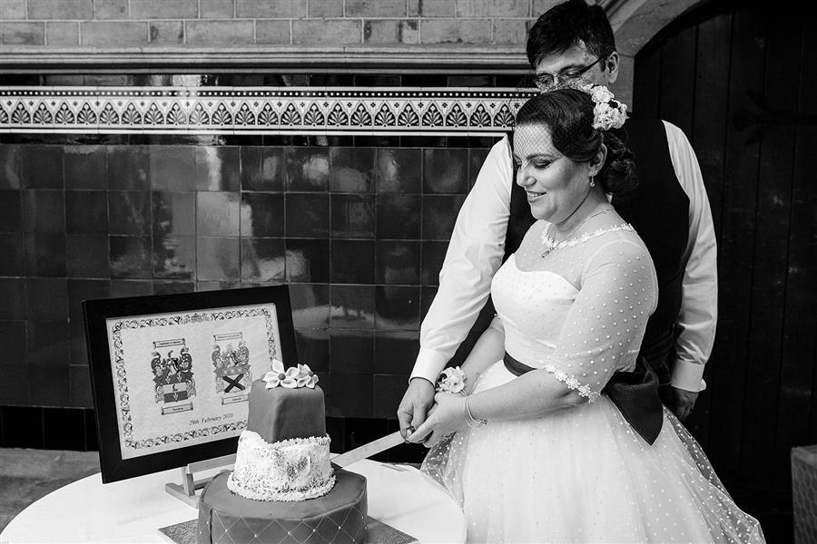 Vintage styled bride cutting wedding cake