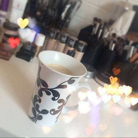 Cup of coffee in front of makeup products and brushes