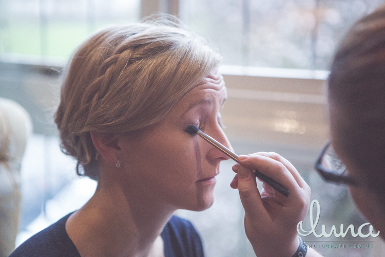 Ms Moo applies dark eyeshadow to a blonde bridesmaid with a plait in her hair