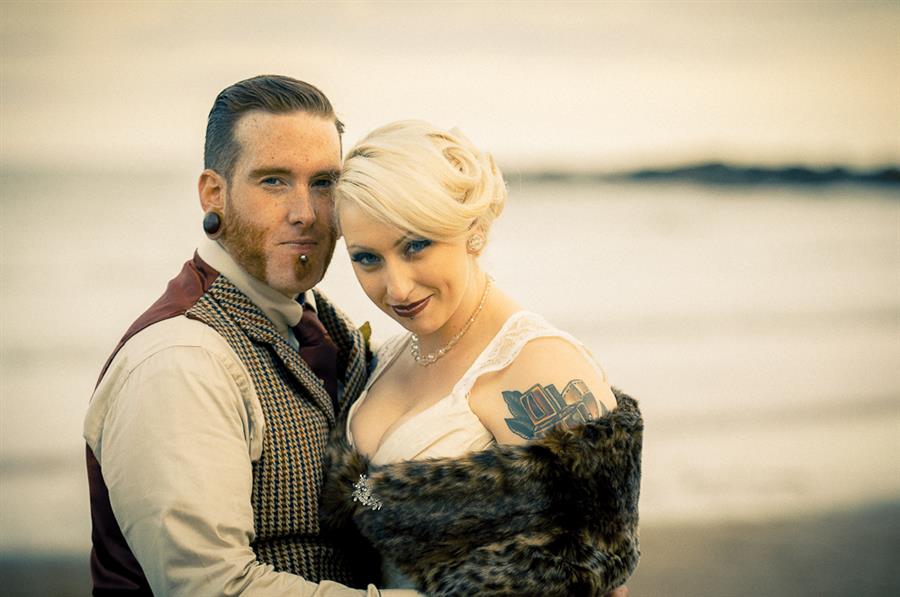 Bride and groom look into camera in front of the sea