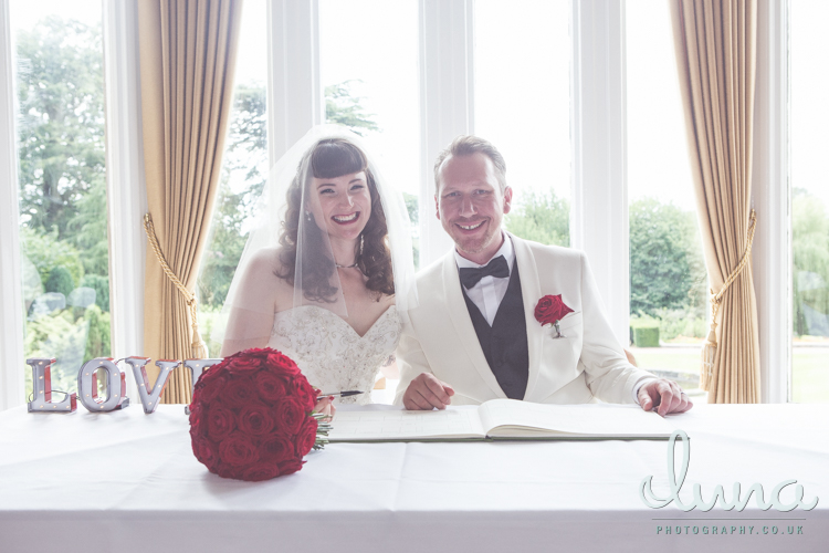 Happy couple look into camera while signing wedding register